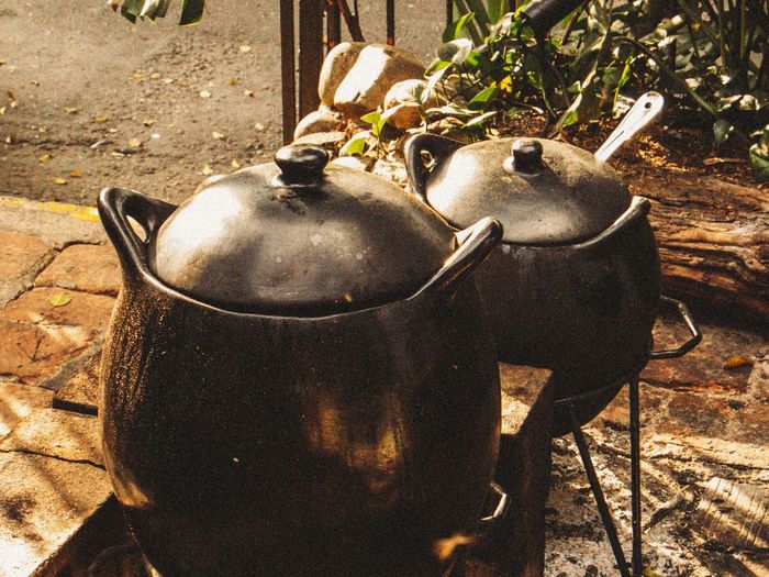 Two earthen pots simmering over open flames.