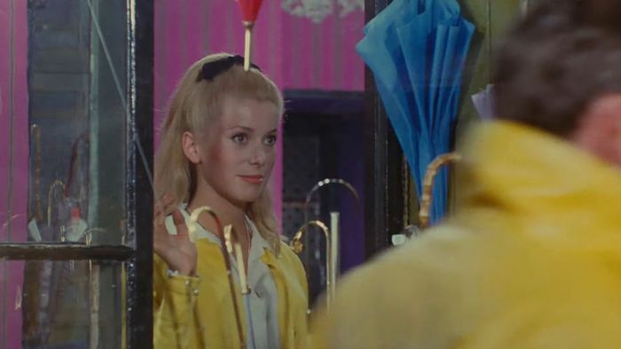 Catherine Deneuve đứng trong một cửa hàng dù ở The Umbrellas of Cherbourg