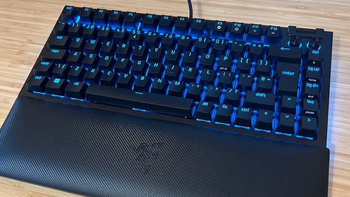 Razer BlackWidow V4 75% với đèn nền màu xanh trên một bàn gỗ