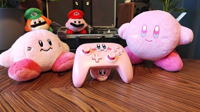 Bộ điều khiển PowerA Kirby cho Nintendo Switch bên cạnh các đồ chơi Kirby