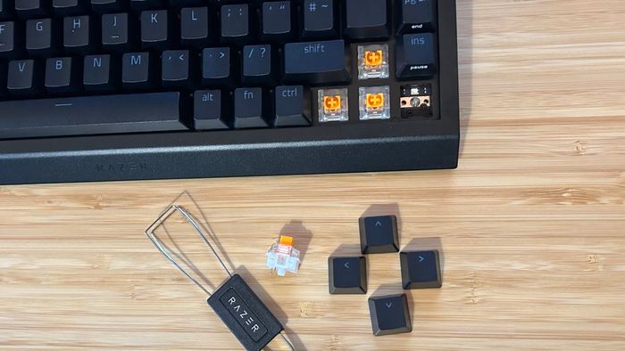 Phía dưới bên phải của bàn phím Razer BlackWidow V4 75% với các nút keycaps và một công tắc được tháo ra và đặt bên dưới