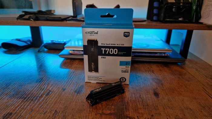 Đánh giá ảnh Crucial T700 Pro với ổ SSD bên cạnh bao bì trên một bàn chơi game