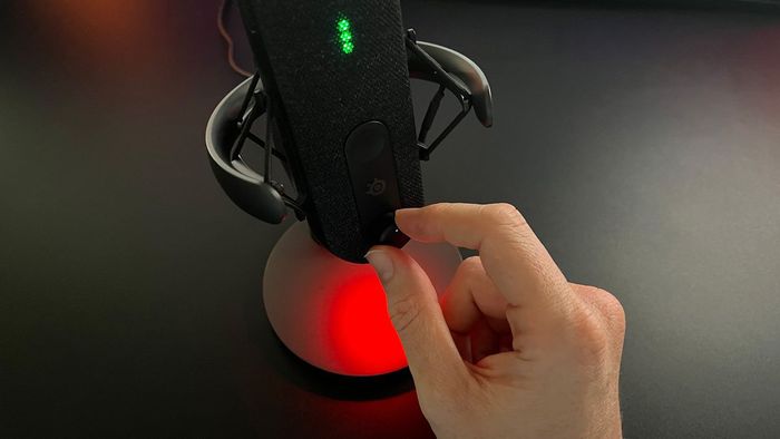 Hình ảnh đánh giá SteelSeries Alias hiển thị người đánh giá điều chỉnh một trong các đĩa điều chỉnh của micro.