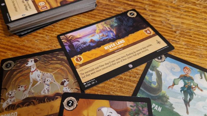 Một bộ sưu tập các lá bài từ Disney Lorcana Into the Inklands, rải rác trên một bàn gỗ