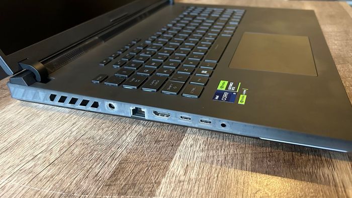 Mẫu Asus ROG Strix Scar 18 mặt bên hiển thị nhựa trong suốt và cổng kết nối trên một bàn làm từ gỗ