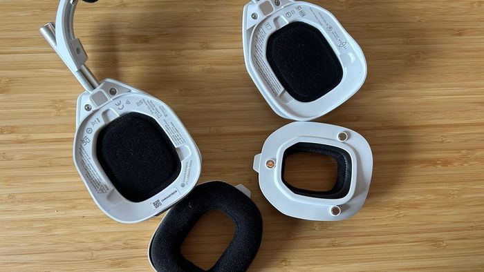 Tai nghe Astro A50 X với đệm đã được gỡ ra và đặt sang một bên trên bàn làm việc gỗ