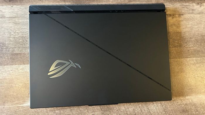 Chiếc Asus ROG Strix Scar 18 đậy nắp trên một cái bàn gỗ