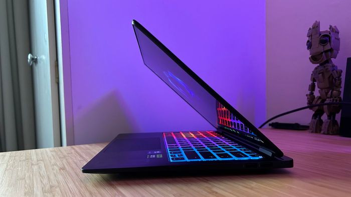 Laptop chơi game HP Omen Transcend 14 đã đóng một nửa trên một bàn gỗ với ánh sáng RGB và màn hình bật