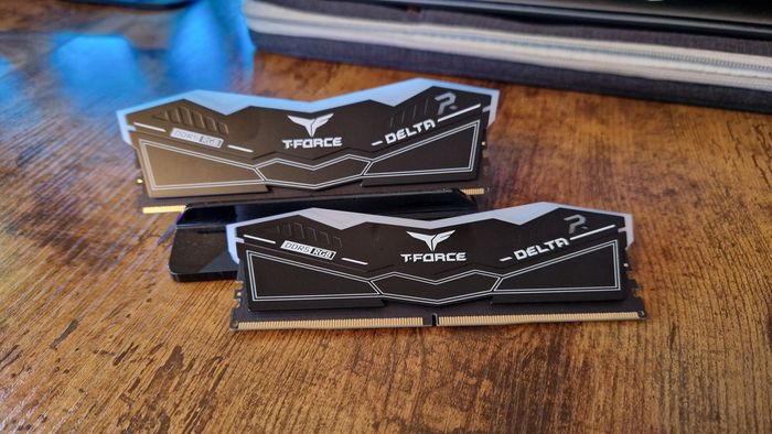 Hình ảnh đánh giá T-Force Delta RGB DDR5 của hai thanh RAM trên một bàn làm bằng gỗ