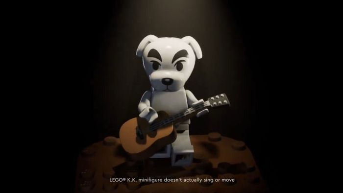 Lego K.K. Slider đang ngồi trên một chiếc ghế với một cây đàn guitar, với một thông báo miêu tả dọc theo phần dưới của hình ảnh