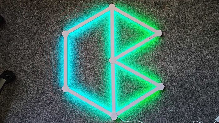 Bộ kit Nanoleaf Lines được thiết lập đặt trên sàn với ánh sáng màu xanh