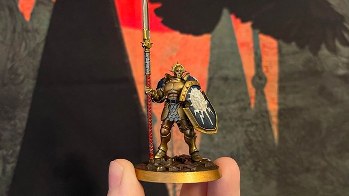 Miniature Stormcast Eternal Vindictor đã được tôi tô màu. Nó có giáp vàng và một cái khiên màu xanh trắng.