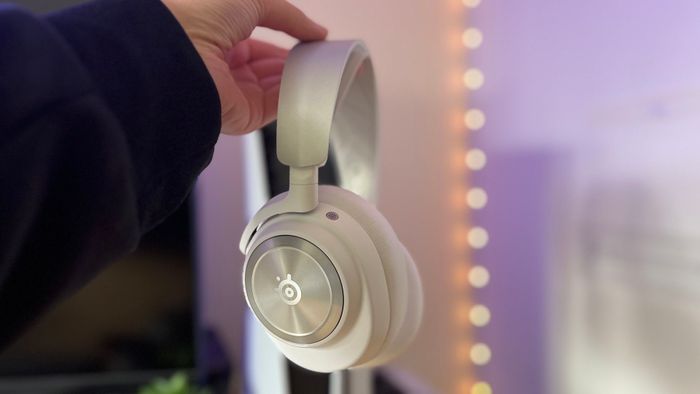SteelSeries Arctis Nova Pro Wireless màu trắng được cầm trước một PS5