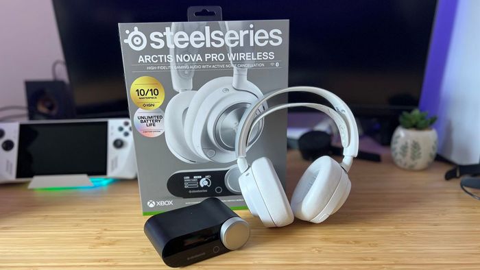 SteelSeries Arctis Nova Pro Wireless màu trắng với bao bì và hub trên một bàn làm bằng gỗ