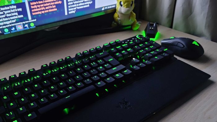 Razer Hunstman V3 Pro trên bàn làm việc bên cạnh chuột, màn hình, Sandshrew plushie và bộ cắm chuột