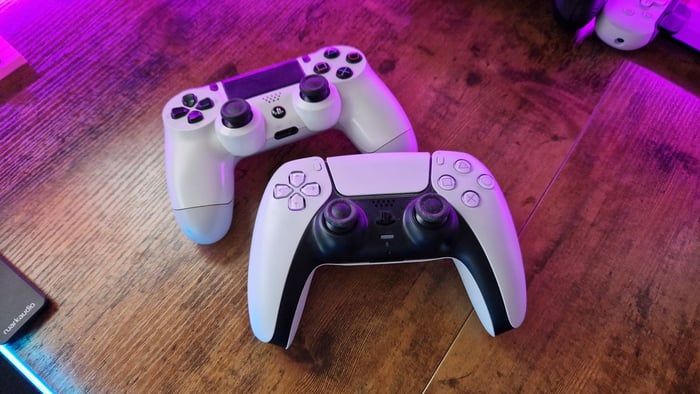 DualShock 4 đặt trên một bàn chơi game trên một tay cầm DualSense