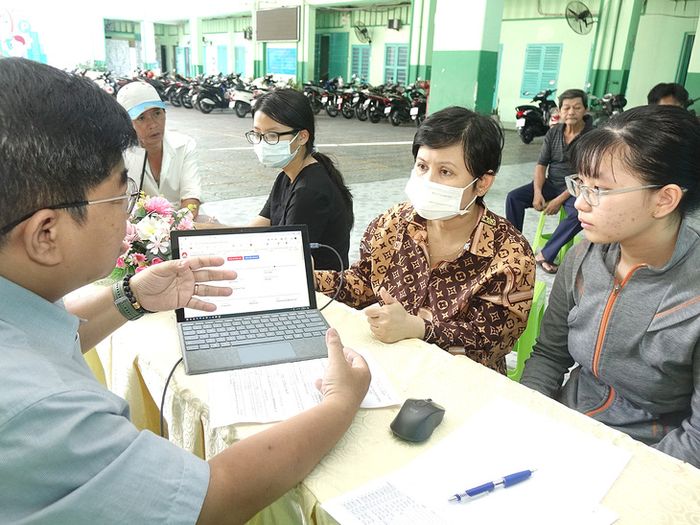 Giáo viên từ Trường THCS Ba Đình, Quận 5, TP.HCM đang hỗ trợ phụ huynh và học sinh đăng ký nguyện vọng tuyển sinh lớp 10 trực tuyến - Ảnh: NHƯ HÙNG