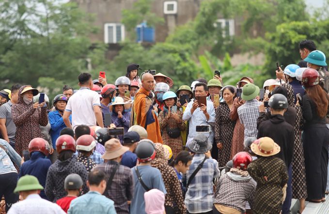 Nhiều người dân đứng xung quanh ông Tú sử dụng điện thoại để quay video tại một bãi đất trống ở xã Cẩm Thịnh, huyện Cẩm Xuyên, vào trưa ngày 17/5. Hình ảnh: Đức Hùng