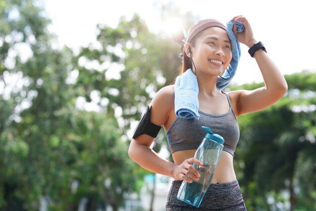 Free photo nữ vận động viên vui vẻ với chai nước và khăn tắm