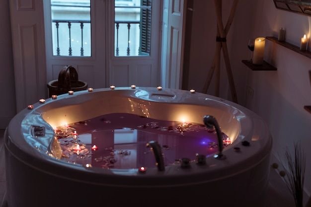 Free photo cánh hoa trên mặt nước trong bồn tắm spa với những cây nến cháy ở mép