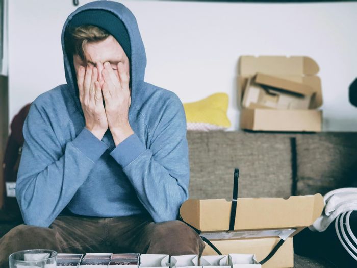 Hình ảnh người đàn ông che kín khuôn mặt bằng cả hai tay khi ngồi trên một băng ghế