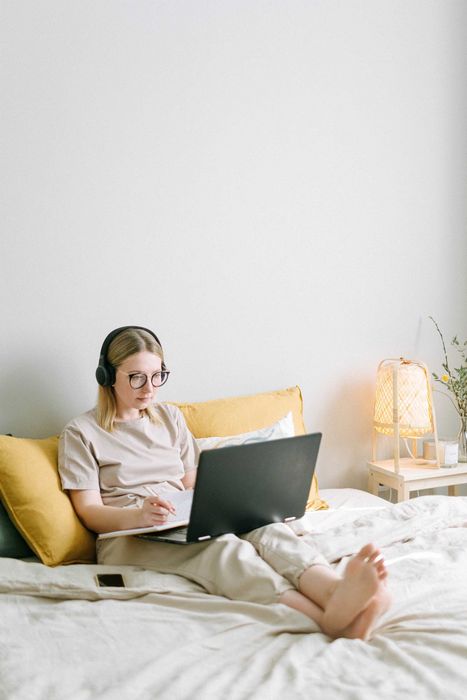 Một cô gái tích cực làm việc không chùng chân trên giường
