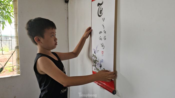 Nghĩa đứng bên tác phẩm thư pháp mà chính mình viết