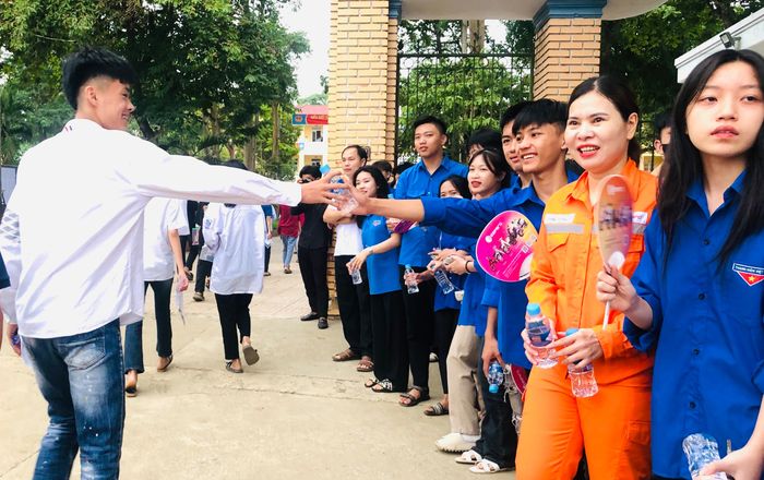 Bên ngoài cổng trường, các thanh niên tình nguyện đã sẵn sàng với nước, sữa, quạt, bánh ngọt để hỗ trợ các thí sinh sau buổi thi.