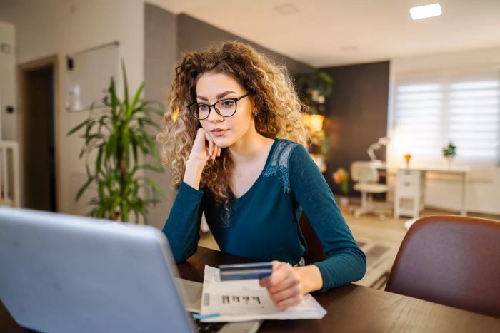 Người phụ nữ trẻ ngồi tại nhà suy nghĩ về các cơ hội arbitrage thẻ tín dụng