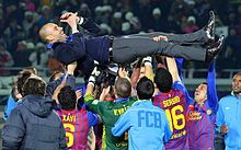 Một nhóm cầu thủ bóng đá, từng thi đấu cho FC Barcelona vào thời điểm chụp ảnh, đang nâng huấn luyện viên của họ sau khi giành FIFA Club World Cup lần thứ hai.