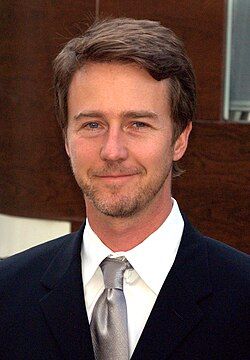 Một bức chân dung của Edward Norton, một người đàn ông da trắng tóc vàng mặc áo sơ mi kẻ sọc trắng. Anh ấy đang mỉm cười về phía máy ảnh.