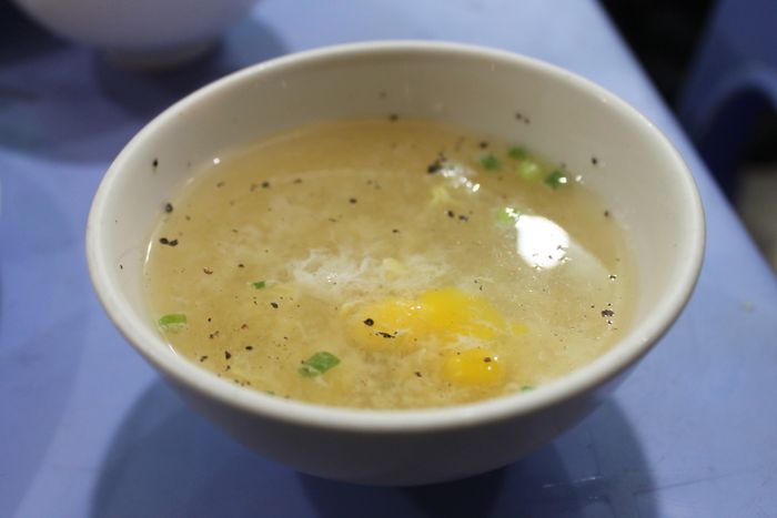 Chén xúp với trứng cút trần hoặc trứng gà non, có màu mỡ gà đặc trưng cùng hành và tiêu, là phần không thể thiếu trong trải nghiệm ẩm thực này - Ảnh: Tô Cường