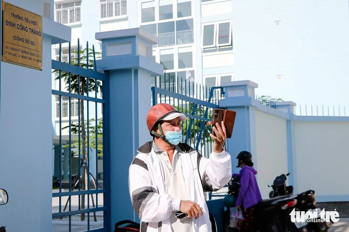 Nhiều phụ huynh háo hức đưa con đến tham quan trường mới và ghi lại khoảnh khắc trước cổng Trường tiểu học Đinh Công Tráng vào chiều 5-8 - Ảnh: CẨM NƯƠNG