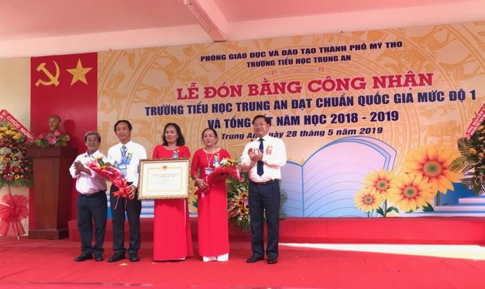 Ông Đặng Thanh Liêm, Bí thư Thành ủy TP. Mỹ Tho (bìa phải) và ông Trần Văn Dũng (Trưởng Phòng Giáo dục Mầm non - Tiểu học Sở Giáo dục - Đào tạo) trao bằng công nhận chuẩn Quốc gia mức 1 cho trường, ảnh 1