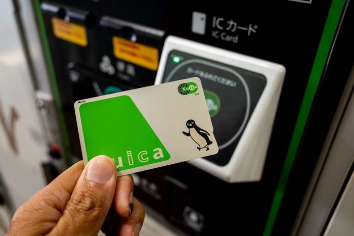 Cận cảnh một tay cầm thẻ SUICA điện tử trước cảm biến để thanh toán mua hàng tại Nagano, Nhật Bản.