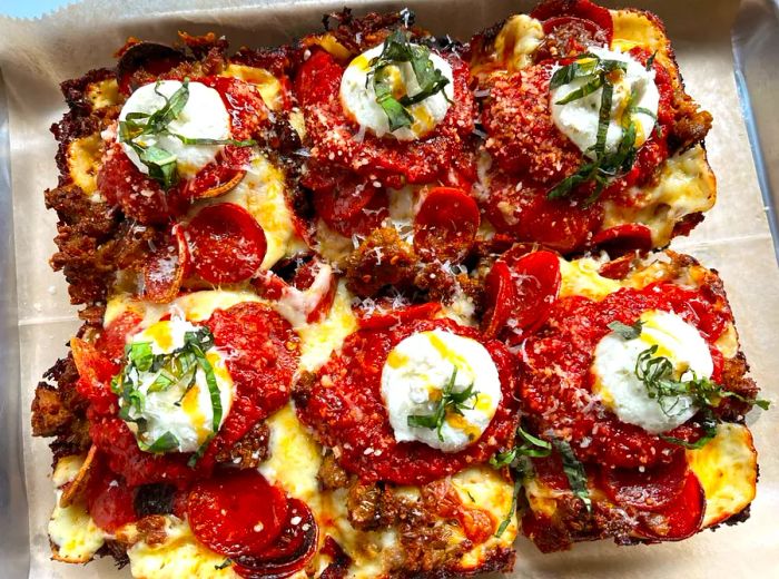 A rectangular pizza sliced into six pieces, each adorned with tomato sauce, pepperoni, and dollops of cheese.