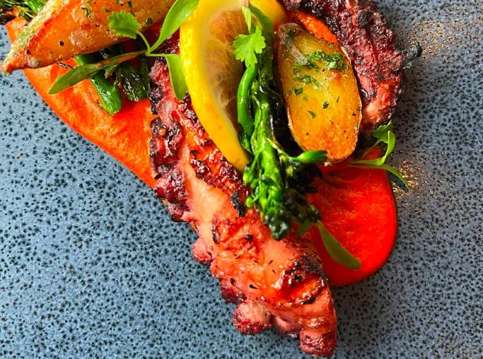 Tender, grilled octopus legs elegantly paired with roasted vegetables.