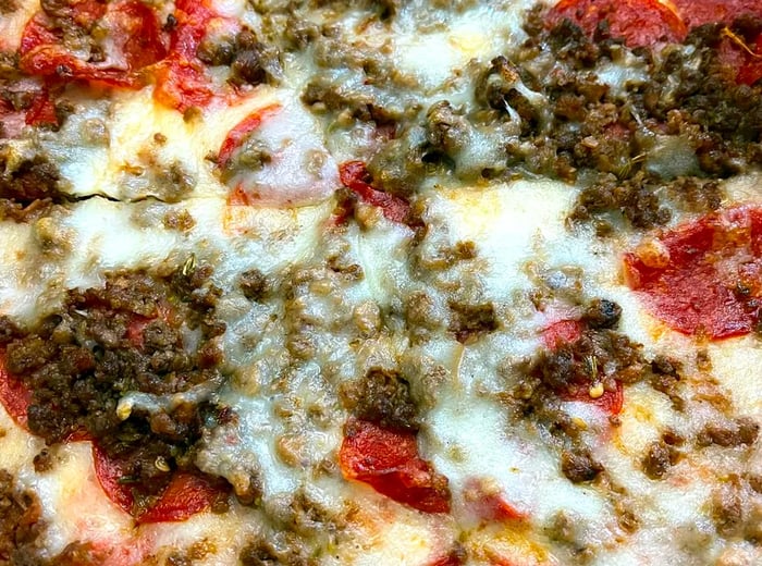 A pizza adorned with a layer of sauce, cheese, and a generous topping of meat.