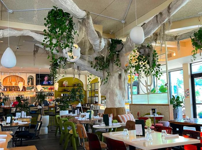 A large artificial tree adorned with oversized egg ornaments hangs over the dining area.