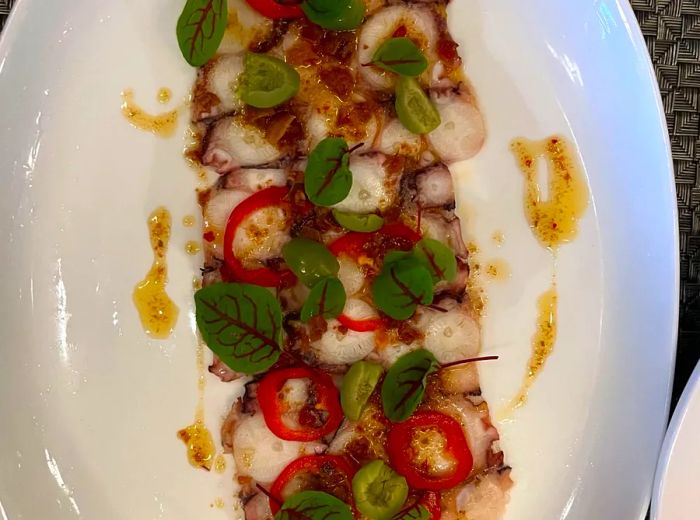 Tender octopus slices layered with a variety of sauces and garnishes.