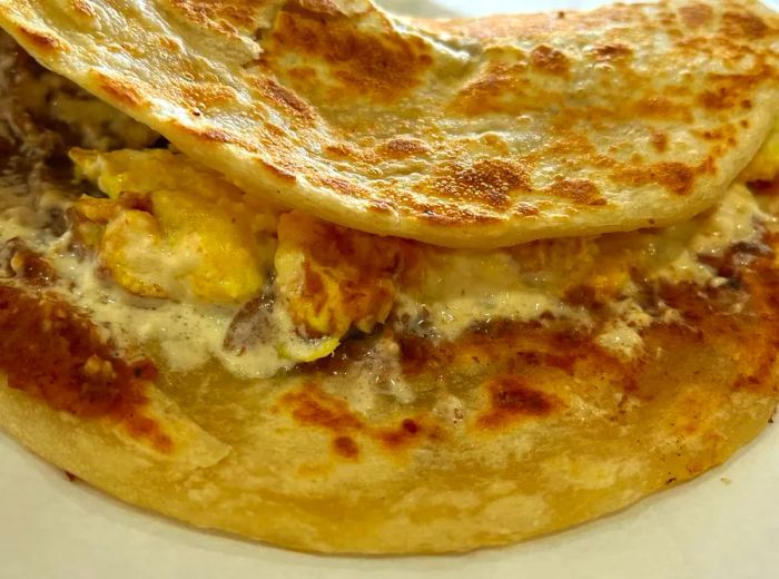 A baleada featuring visible fillings like eggs and beans spilling out.