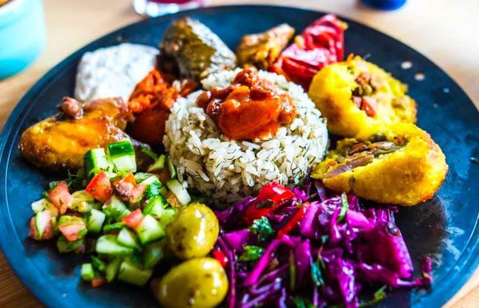 A vibrant mezze platter surrounded by a variety of dishes and a central mound of rice.