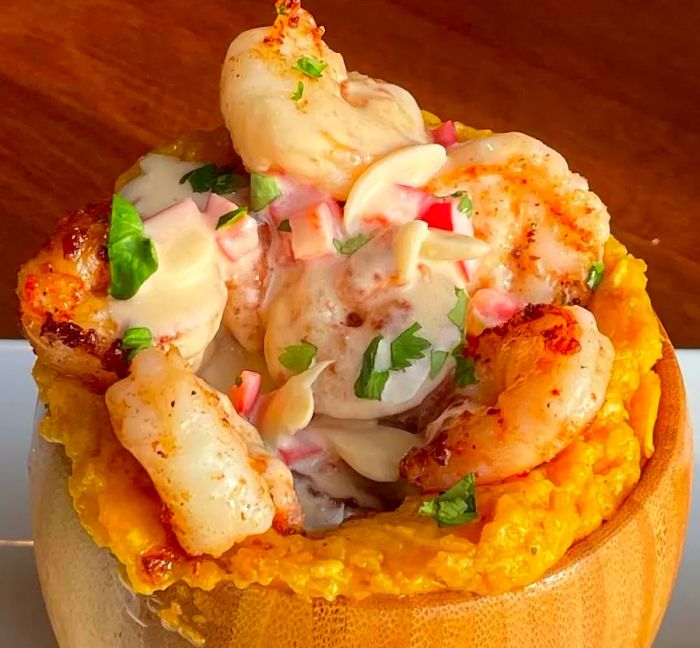 A dish of mofongo, garnished with shrimp in a rich, creamy sauce.