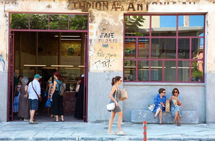 Shoppers outside a bakery with a concrete exterior.