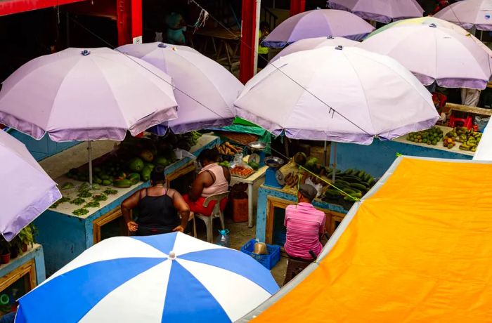 Vendors selling fresh produce peek through the gaps between sun umbrellas.