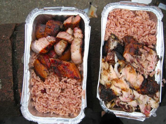 Two containers of jerked meat served with rice for takeout.