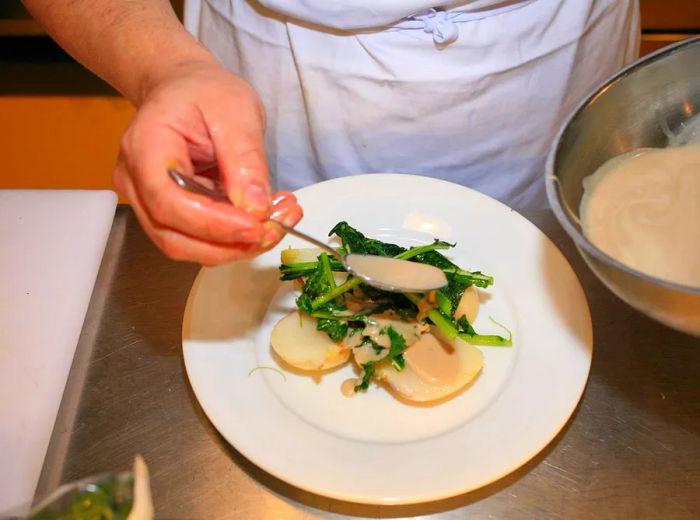 A chef carefully arranges a dish at Cafe Cecilia.