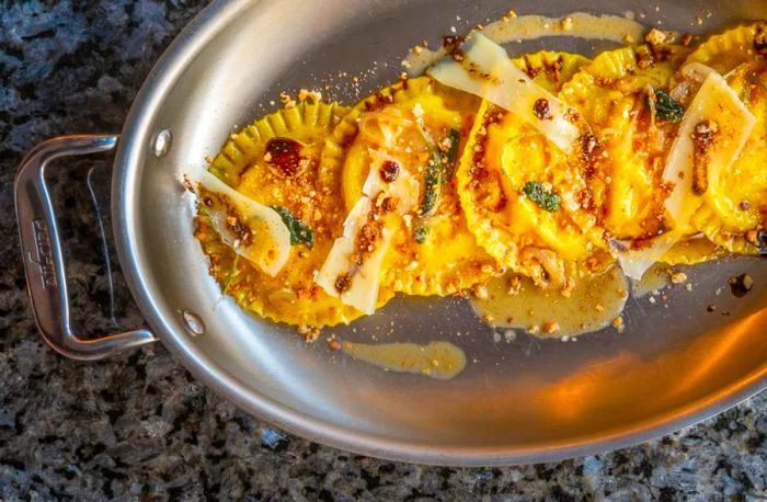 <div>
                
                  <div>A gleaming silver platter showcasing bright yellow ravioli from a bird's-eye view.</div>
                </div>