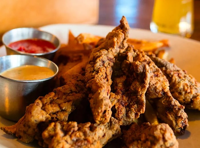 <div>
                
                  <div>A plate of crispy, dark-fried steak strips accompanied by dipping sauces.</div>
                </div>