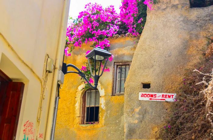 A 'Rooms for Rent' sign displayed on a wall in a Cretan city.